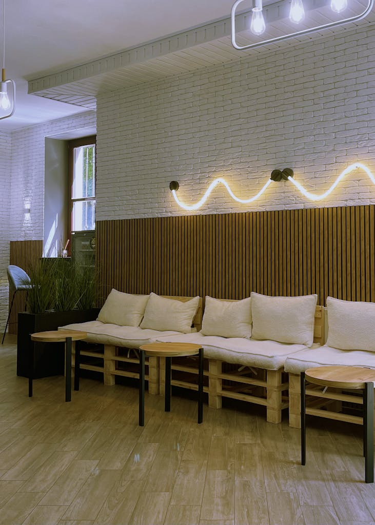 A stylish and cozy cafe interior featuring modern seating with soft cushions, wooden decor, and ambient lighting.
